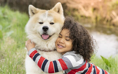 Lächelnder Junge umarmt Hund in der Natur - JCCMF01347