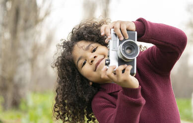 Cute boy holding vintage camera in nature - JCCMF01350