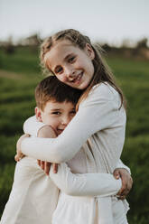 Loving brother and sister embracing at grassy field - GMLF01061