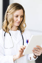 Ärztin mit digitalem Tablet in einer medizinischen Klinik - GIOF11621