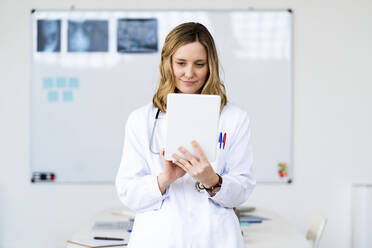 Weibliche medizinische Fachkraft, die zu Hause ein digitales Tablet benutzt - GIOF11623