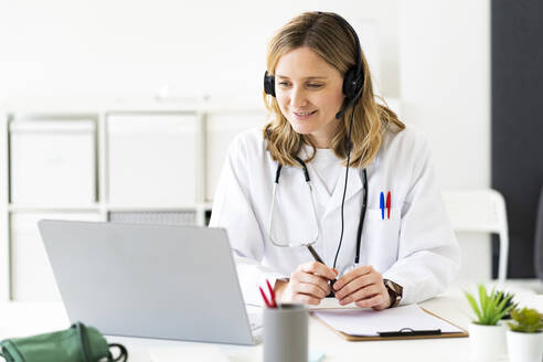 Blonde Ärztin bei der Online-Beratung am Laptop in einer medizinischen Klinik - GIOF11636