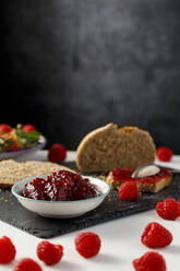 Brotscheiben, frische Himbeeren und eine Schale Himbeermarmelade - IFRF00440