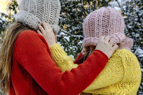 Girls pulling down knit hats of each other - OGF00930