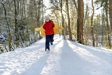 Glückliches Mädchen in warmer Kleidung, das im Winter im Schnee läuft - OGF00934
