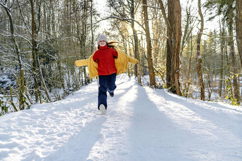 Happy girl in warm clothing running on snow during winter - OGF00934
