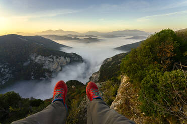 Man sitting on mountain against sky during sunrise at Furlo Gorge, Marche, Italy - LOMF01238