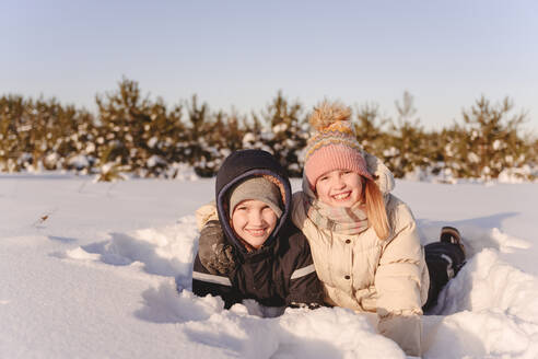 Cute Geschwister liegen auf Schnee gegen den Himmel bei Sonnenuntergang - EYAF01519