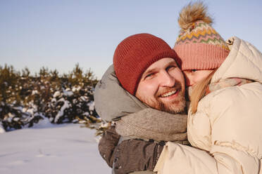 Lächelnder Vater, der seine Tochter in warmer Kleidung im Winter umarmt - EYAF01521
