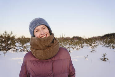 Lächelnde Frau in warmer Kleidung gegen den Himmel im Winter - EYAF01528
