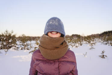 Lächelnde Frau mit Strickmütze gegen den Himmel im Winter - EYAF01529