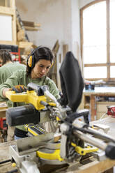Schreinerin bei der Arbeit mit Holzbearbeitungsgeräten in der Werkstatt - VABF04246