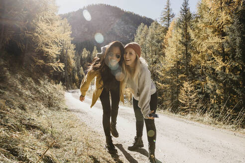 Playful friends laughing while standing together in forest - LHPF01397