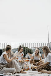 Friends enjoying adundant picnich on rooftop trerrace - LHPF01411