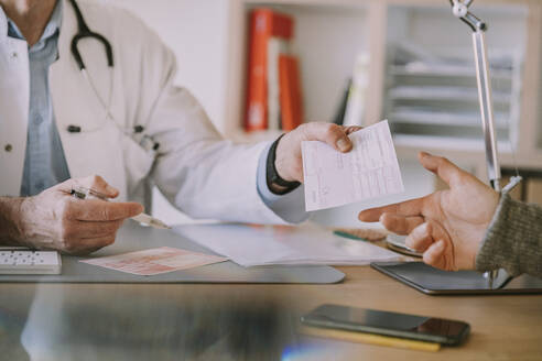 Doctor giving prescription to patient at doctor's office - MFF07493