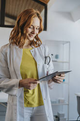 Mitarbeiterin im Gesundheitswesen bei der Arbeit an einem digitalen Tablet in einer Klinik - MFF07526