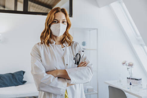 General practitioner with arms crossed standing at clinic - MFF07535