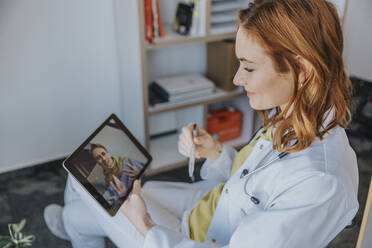 Allgemeinmediziner im Gespräch mit einem Patienten per Videoanruf über ein digitales Tablet in der Praxis - MFF07545
