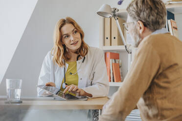 General practitioner with digital tablet talking to patient at doctor's office - MFF07562