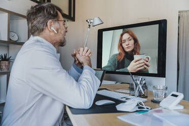 Männlicher Arzt im Gespräch mit einem Patienten über Computer per Videoanruf in einer Klinik - MFF07580