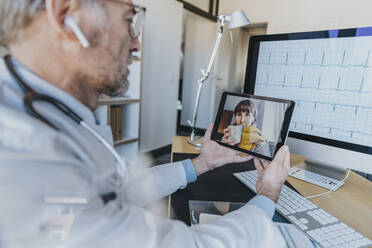 Allgemeinmediziner im Gespräch mit einem Patienten per Videoanruf über ein digitales Tablet in der Arztpraxis - MFF07592