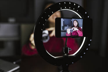 Young female vlogger explaining new camera in darkroom - LJF02104