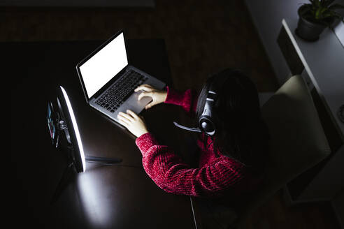 Female vlogger using laptop in darkroom - LJF02114