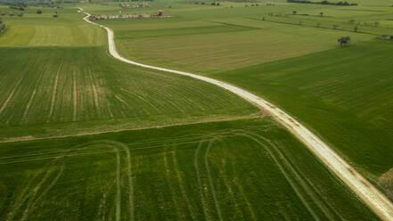 Dirt road amidst green fields seen from above - ACPF01182