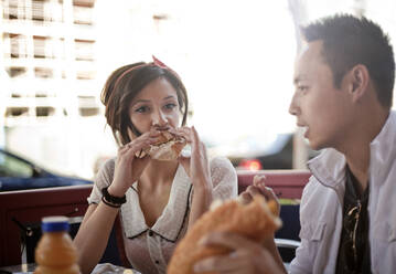 Schöne Frau und gut aussehender Mann essen Sandwich in einem Straßencafé - AJOF01238