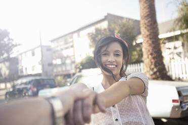 Boyfriend holding hands of smiling girlfriend at street - AJOF01244