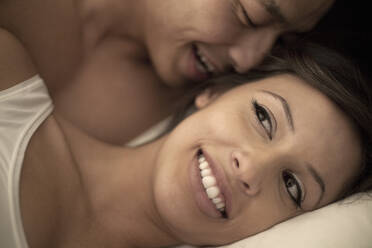 Boyfriend whispering in smiling girlfriend's ear at bedroom - AJOF01254