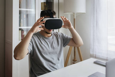 Männlicher Unternehmer mit einem Virtual-Reality-Headset, während er in seinem Büro sitzt - MGOF04686