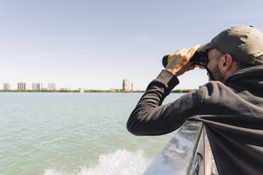 USA, Florida, Sanibel, Mann betrachtet das Meer durch ein Fernglas - GEMF04718