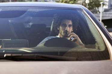 Thoughtful entrepreneur holding smart phone while sitting in car - VEGF04051