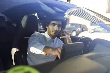 Geschäftsmann, der GPS benutzt, während er im Auto mit seinem Smartphone spricht, gesehen durch die Windschutzscheibe - VEGF04052