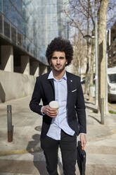 Gutaussehender Geschäftsmann mit Kaffeetasse auf der Straße an einem sonnigen Tag - VEGF04068