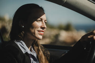 Geschäftsfrau lächelnd beim Autofahren an einem sonnigen Tag - DMGF00534