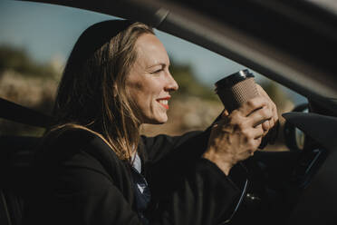 Entrepreneur having coffee while sitting in car on sunny day - DMGF00537