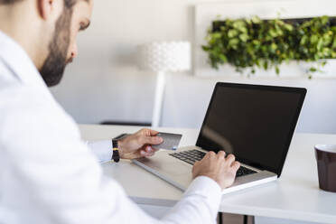 Male entrepreneur with credit card using laptop at office - DIGF14830