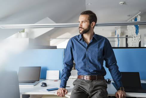 Nachdenklicher Geschäftsmann am Schreibtisch sitzend im Büro - DIGF14854