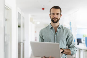 Junger Unternehmer mit Laptop im Büro - DIGF14939