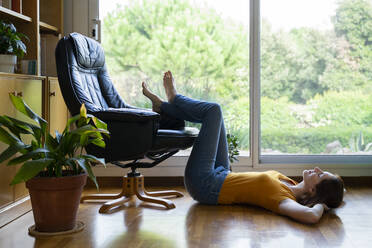 Young woman relaxing while lying on floor at home - AFVF08441