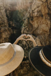 Young women making heart with hands in front of rock formation - ARTF00037