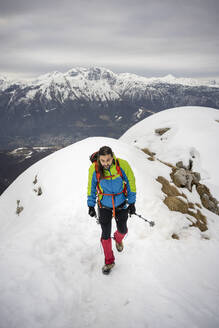 Alpinist beim Wandern mit Wanderstock auf einem schneebedeckten Berg - MCVF00734