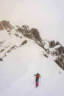 Mann beim Wandern auf einem schneebedeckten Berg im Winter - MCVF00739