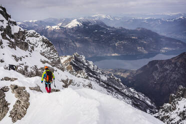 Mann beim Wandern auf einem schneebedeckten Berg im Urlaub - MCVF00742