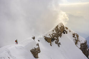 Männlicher Bergsteiger beim Klettern auf einem schneebedeckten Berg gegen den Himmel - MCVF00744