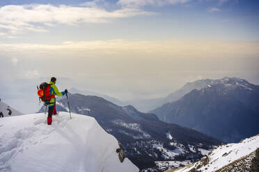 Male alpinist admiring view while standing on snowcapped mountain - MCVF00747