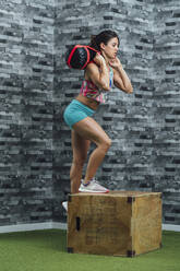 Weibliche Athletin beim Training mit dem Boxsack im Fitnessstudio - MTBF00863