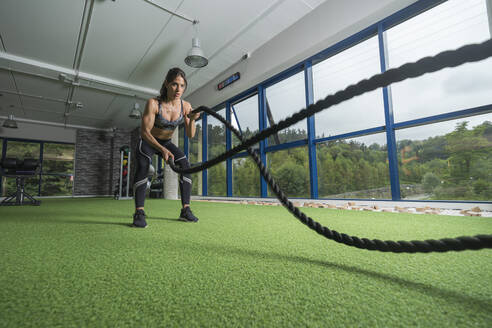 Entschlossene Sportlerin beim Seiltraining im Fitnessstudio - MTBF00866